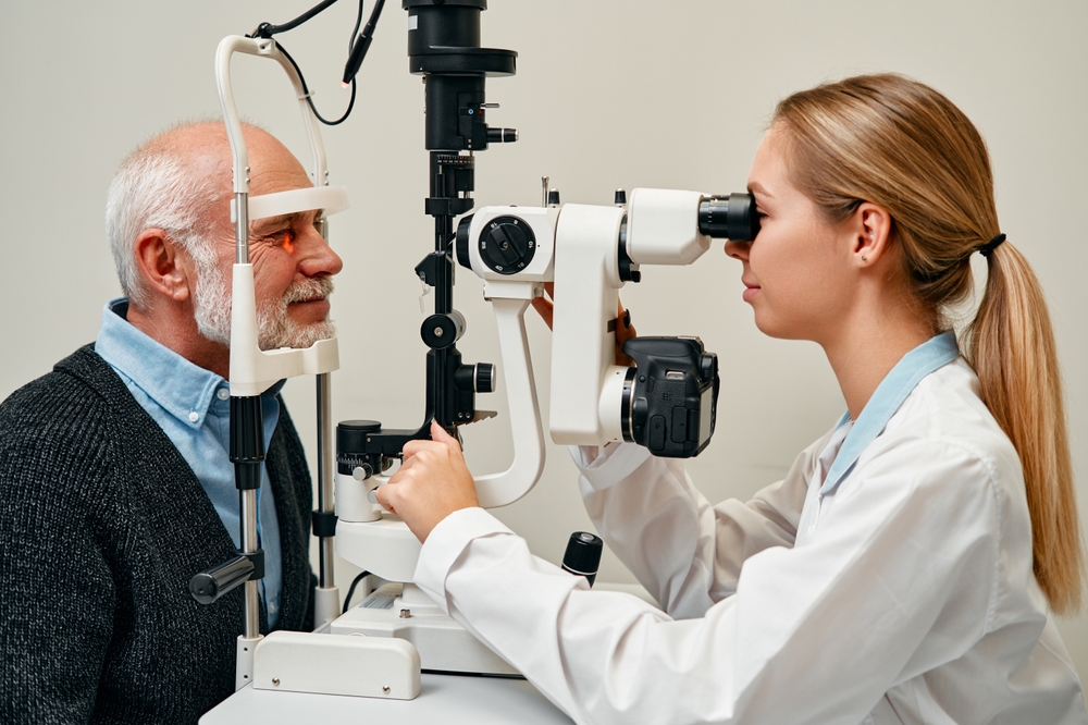 A close-up scene of an optometrist performing a slit lamp examination on an older man, assessing the health of his eyes using specialized diagnostic equipment. - Eye Exams